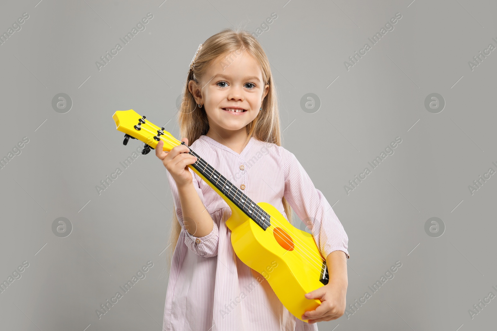 Photo of Little girl with ukulele on gray background