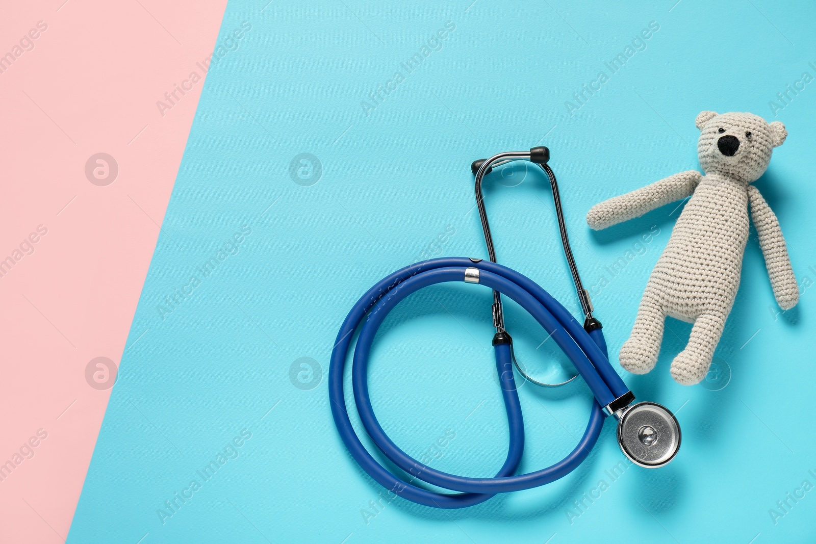 Photo of Pediatrics concept. Toy bear with stethoscope on color background, top view. Space for text