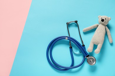 Photo of Pediatrics concept. Toy bear with stethoscope on color background, top view. Space for text