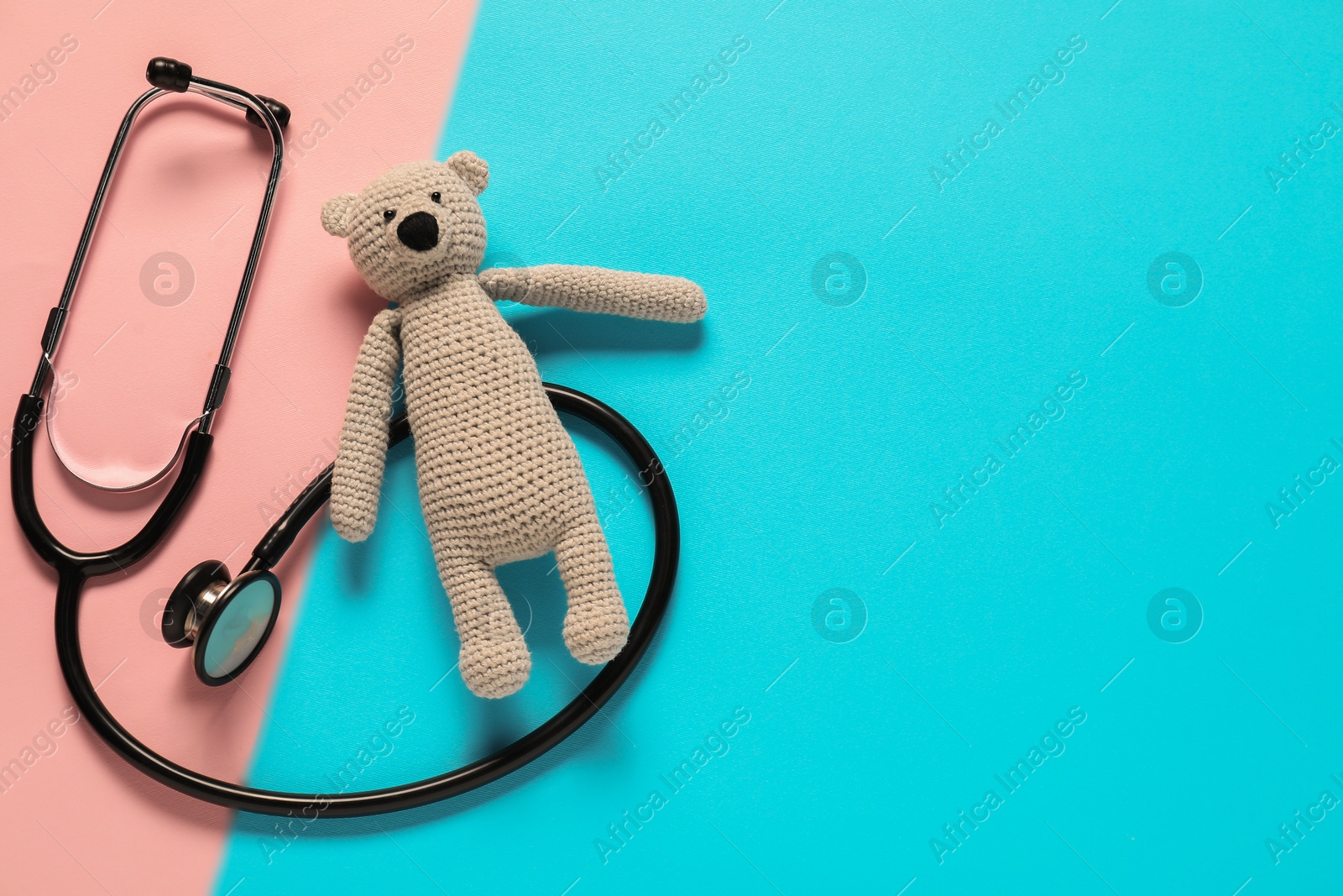 Photo of Pediatrics concept. Toy bear with stethoscope on color background, top view. Space for text