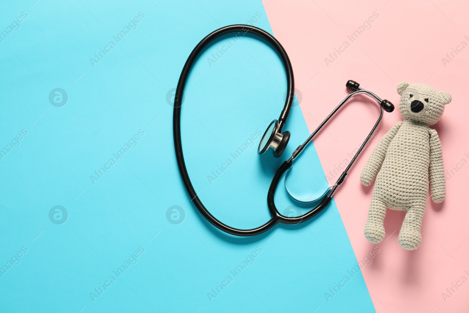 Photo of Pediatrics concept. Toy bear with stethoscope on color background, top view. Space for text