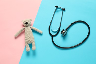 Photo of Pediatrics concept. Toy bear with stethoscope on color background, flat lay