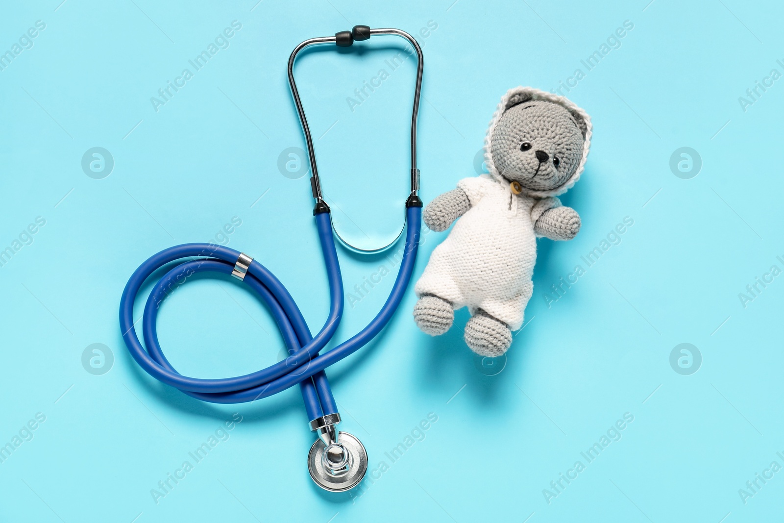 Photo of Pediatrics concept. Toy bear with stethoscope on light blue background, top view