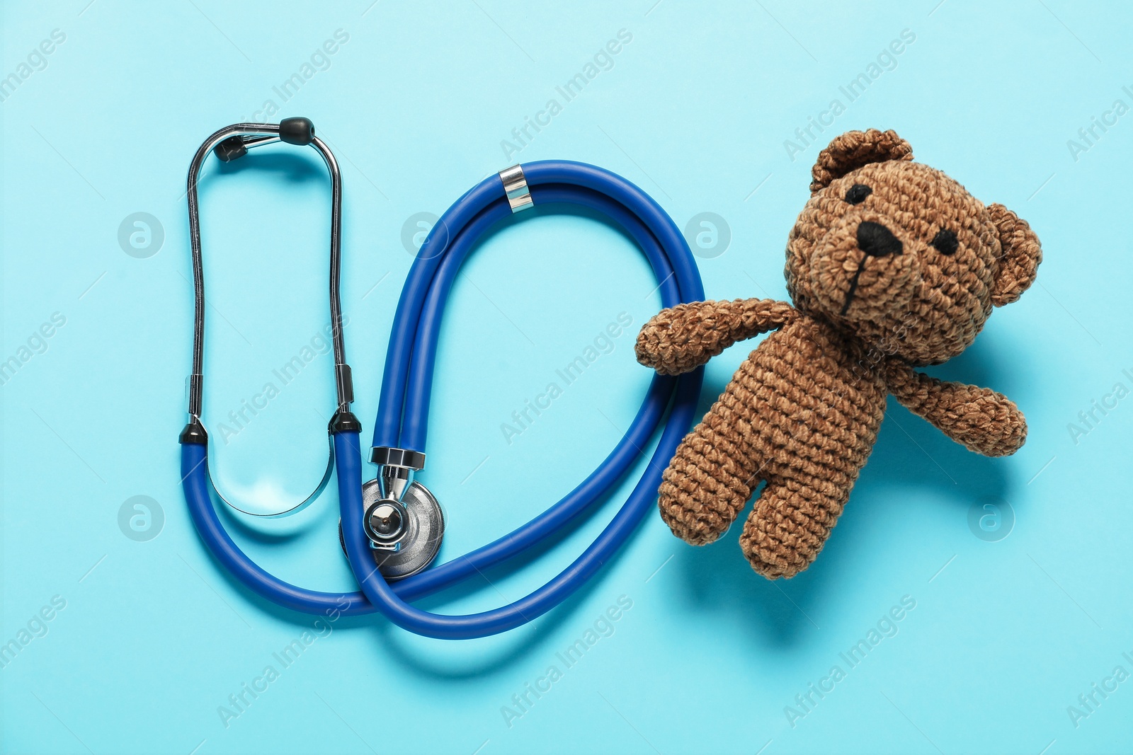 Photo of Pediatrics concept. Toy bear with stethoscope on light blue background, top view