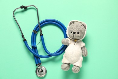 Photo of Pediatrics concept. Toy bear with stethoscope on turquoise background, top view