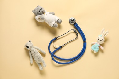 Photo of Pediatrics concept. Bunny and bear toys with stethoscope on beige background, top view