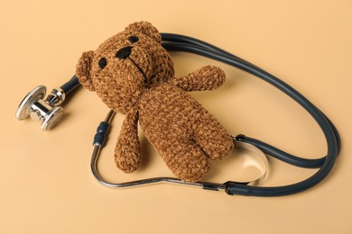 Photo of Pediatrics concept. Toy bear with stethoscope on beige background