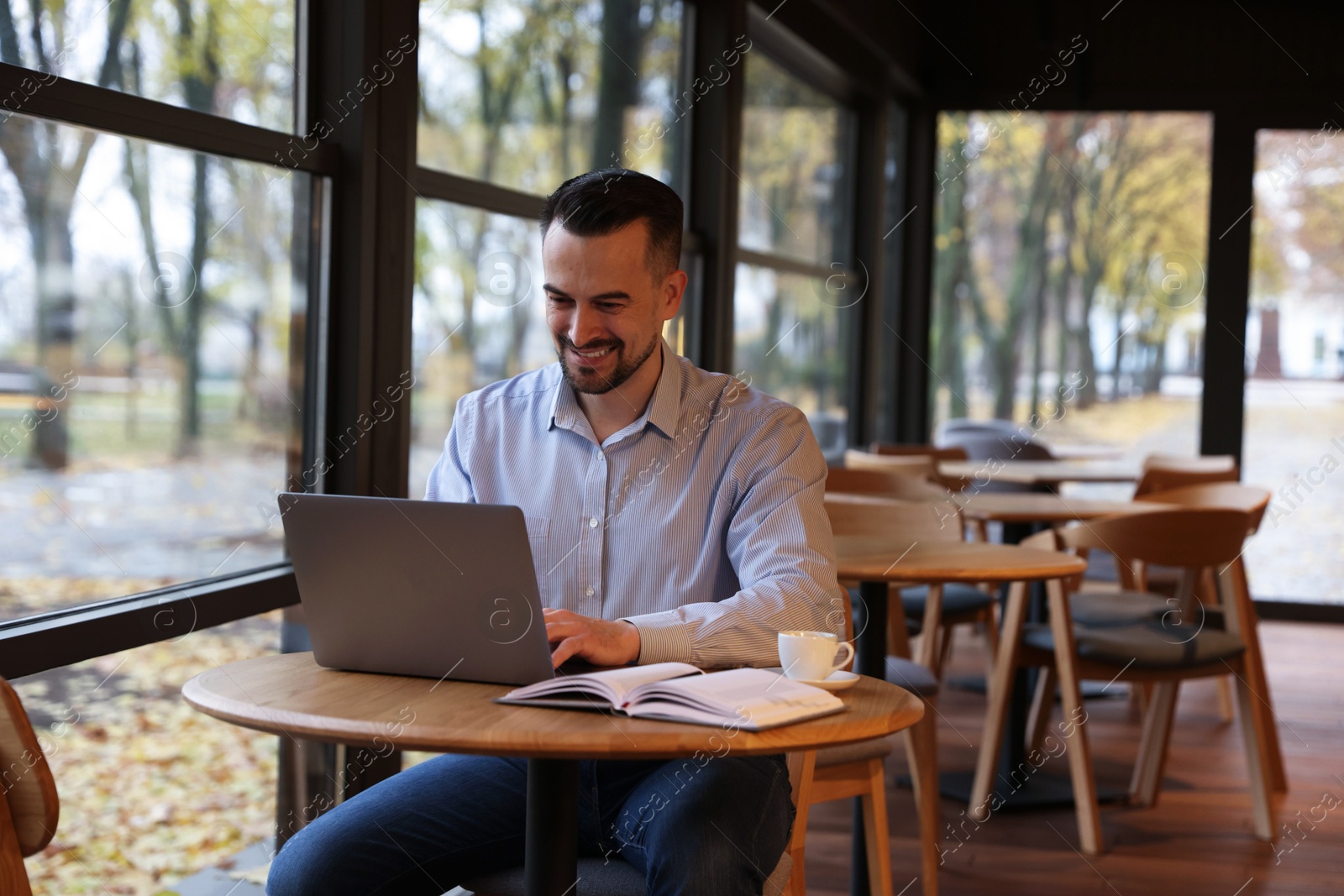 Photo of Man working on laptop at table in cafe