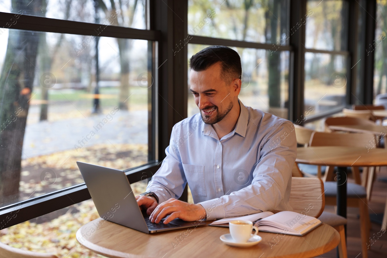 Photo of Man working with laptop at table in cafe