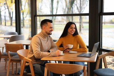 Photo of Colleagues with laptop working together at table in cafe