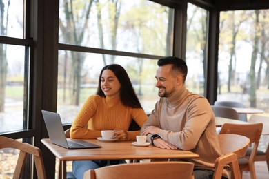 Photo of Colleagues with laptop working together at table in cafe