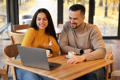 Photo of Colleagues with laptop working together at table in cafe