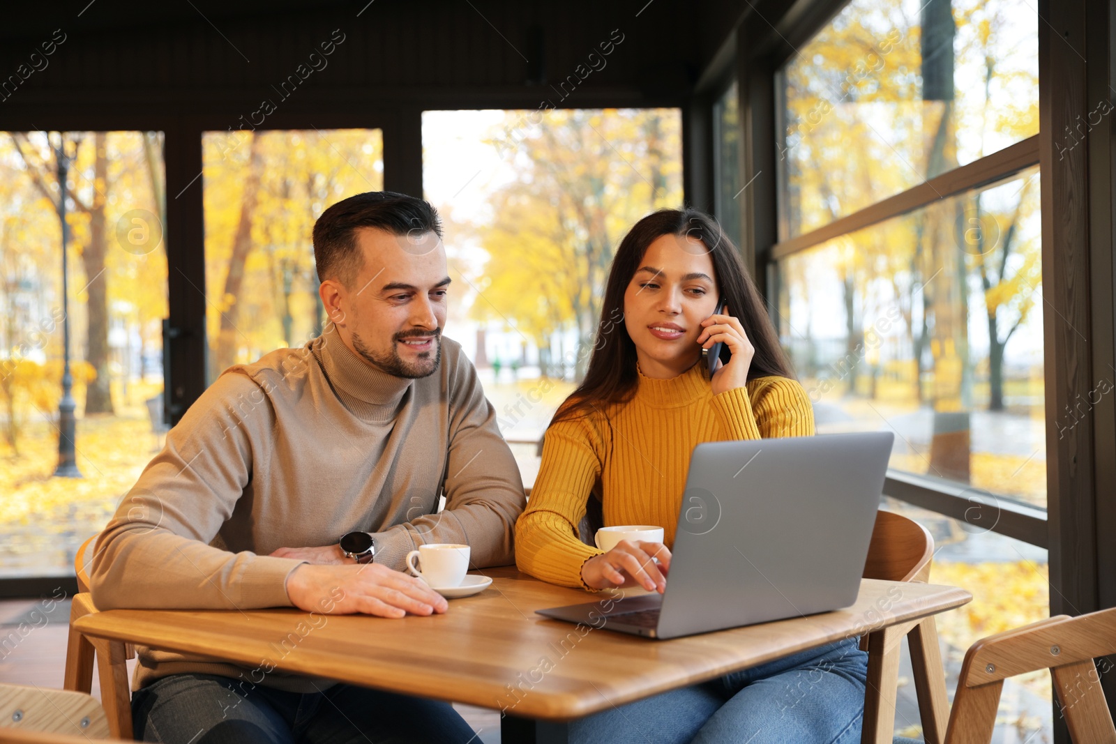 Photo of Colleagues with laptop working together at table in cafe