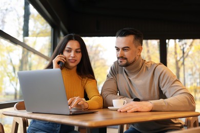 Photo of Colleagues with laptop working together at table in cafe