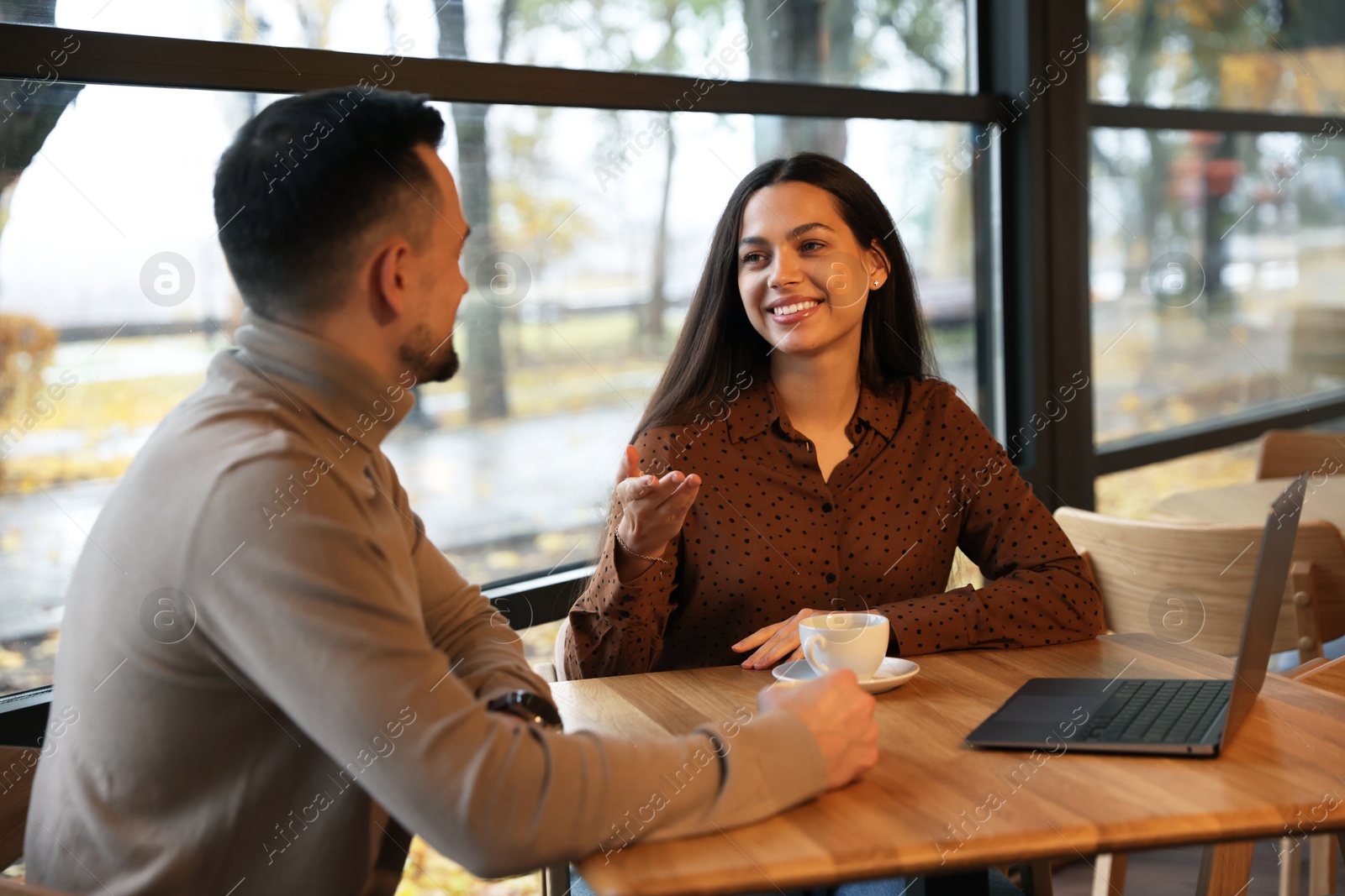 Photo of Colleagues with laptop working together at table in cafe