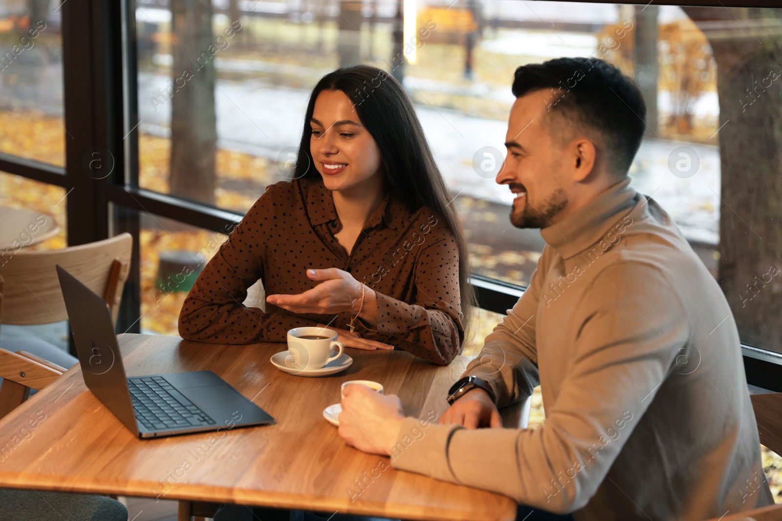 Photo of Colleagues with laptop working together at table in cafe