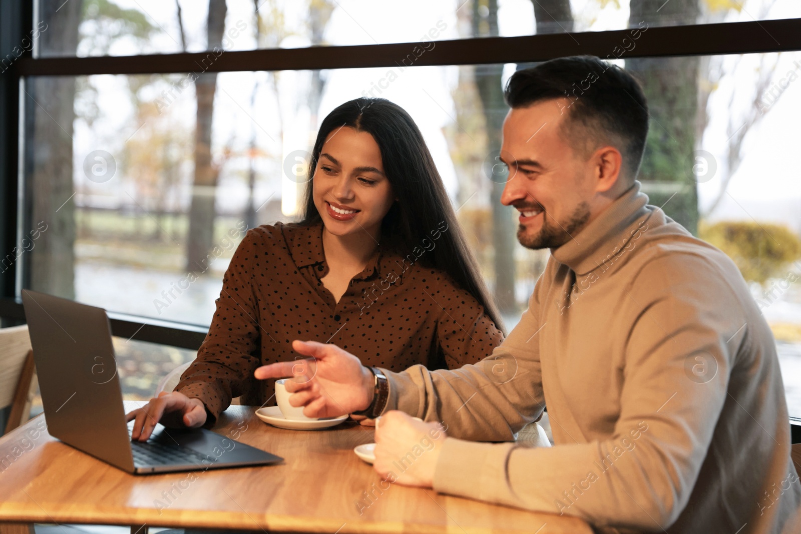 Photo of Colleagues with laptop working together at table in cafe