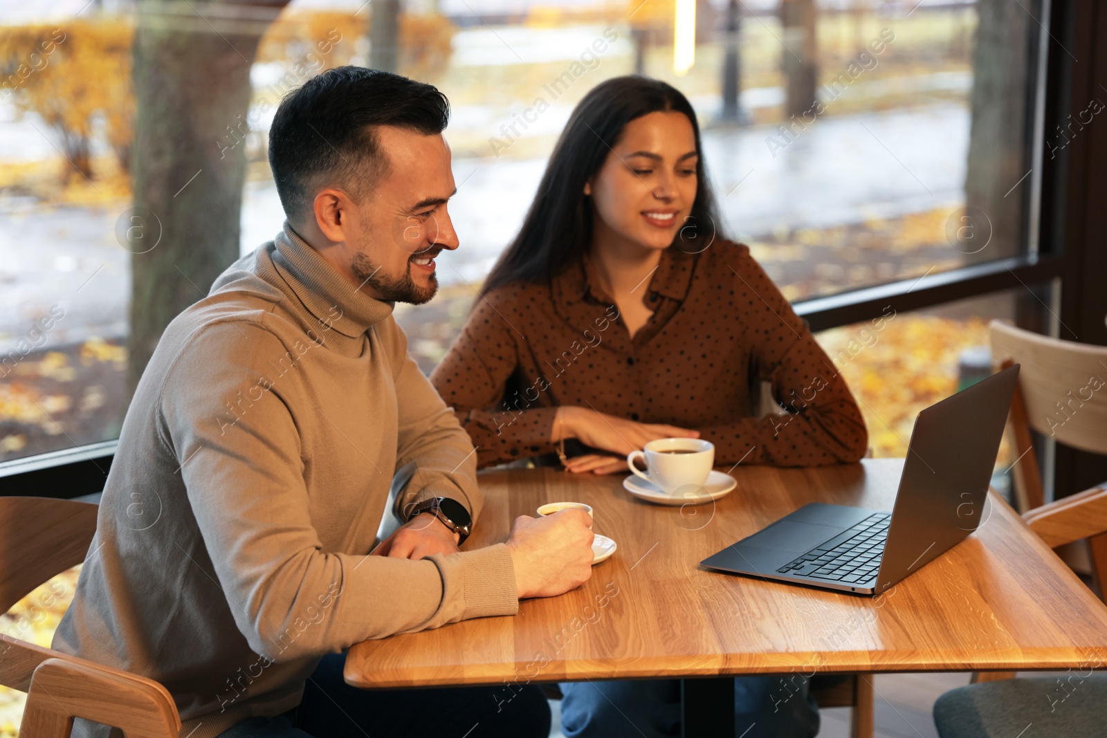 Photo of Colleagues with laptop working together at table in cafe