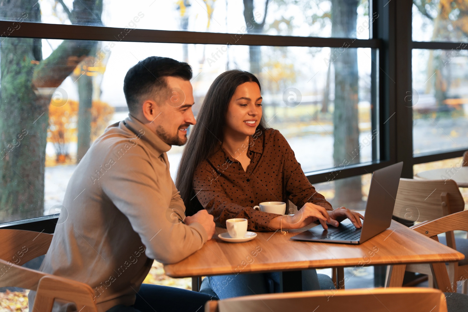 Photo of Colleagues with laptop working together at table in cafe