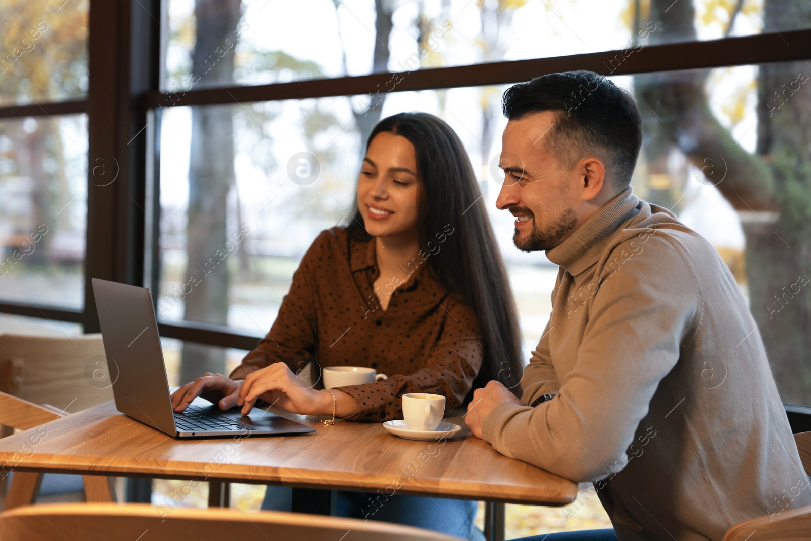 Photo of Colleagues with laptop working together at table in cafe