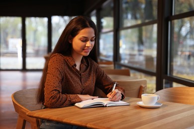 Photo of Woman taking notes at table in cafe