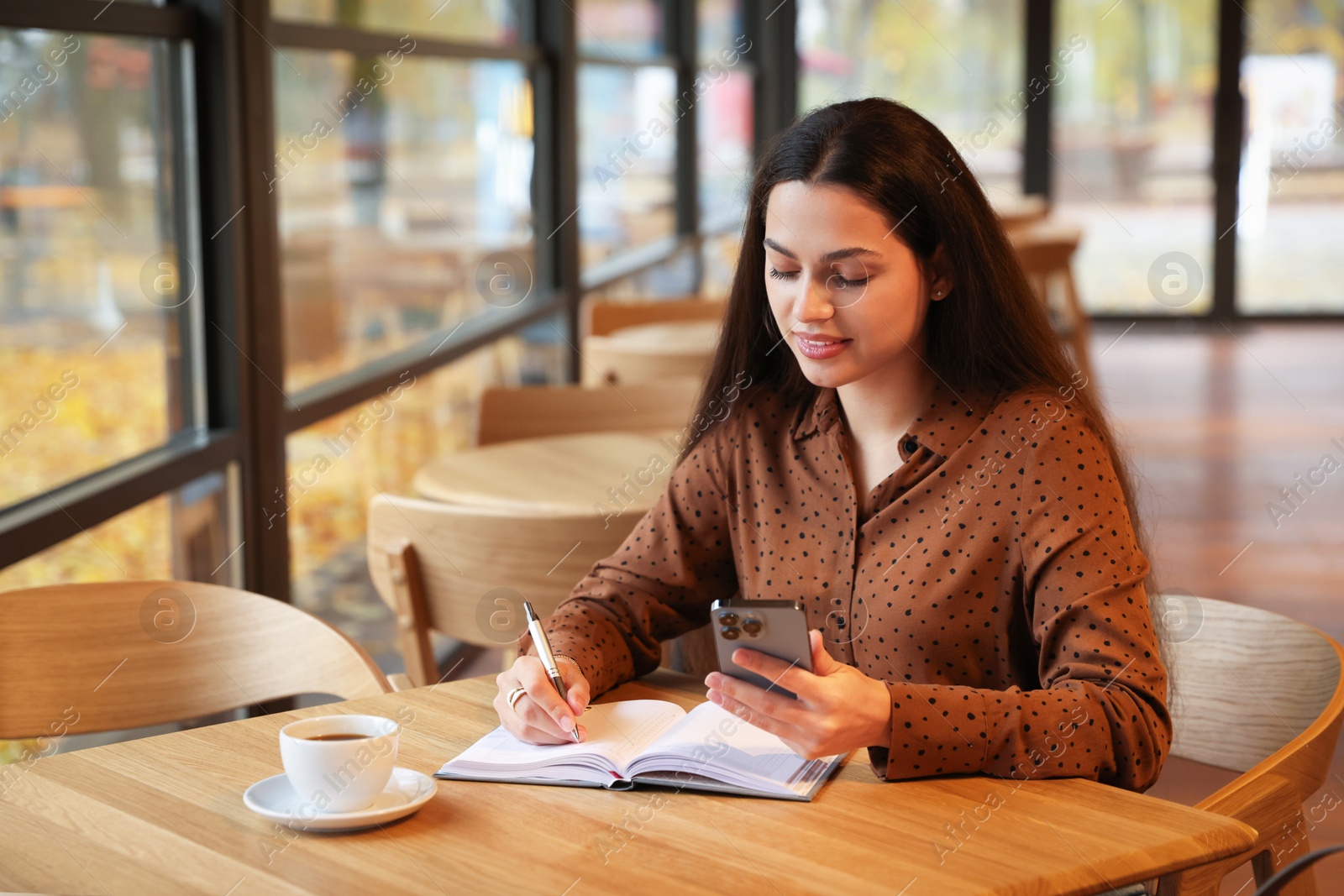 Photo of Woman using smartphone while working at table in cafe, space for text