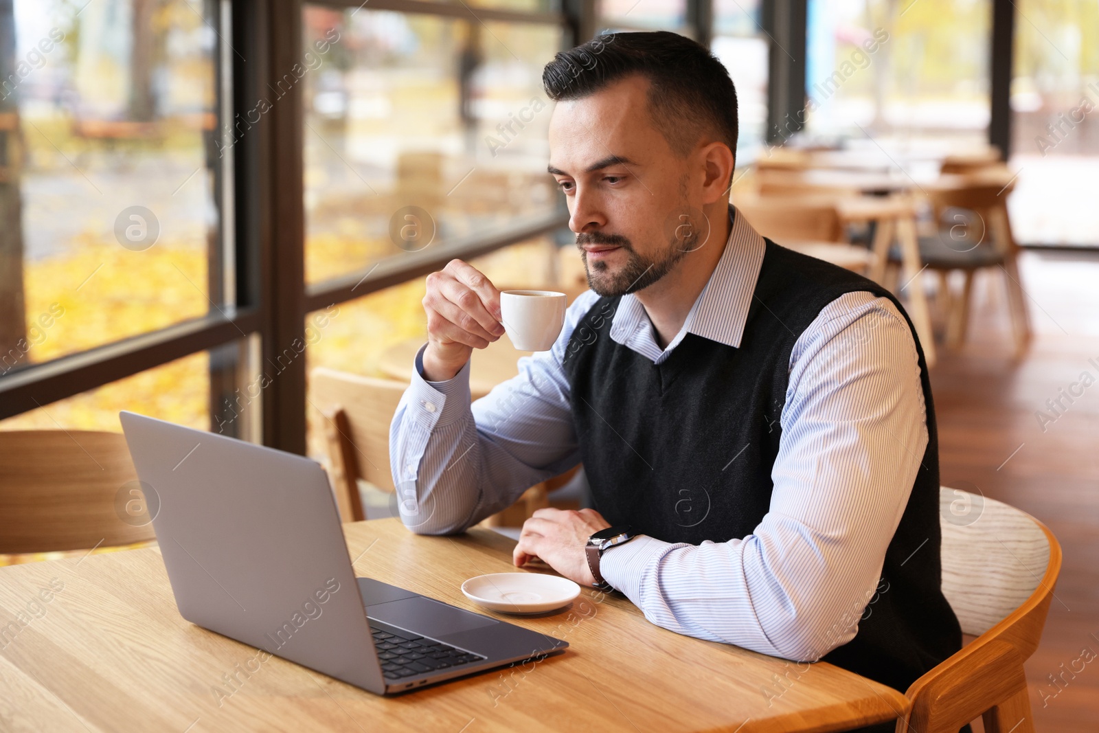 Photo of Man with cup of coffee working at table in cafe