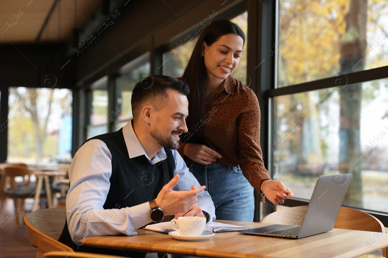 Photo of Colleagues with laptop working together in cafe