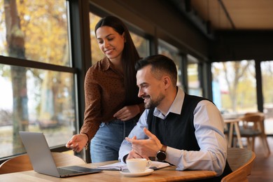 Photo of Colleagues with laptop working together in cafe