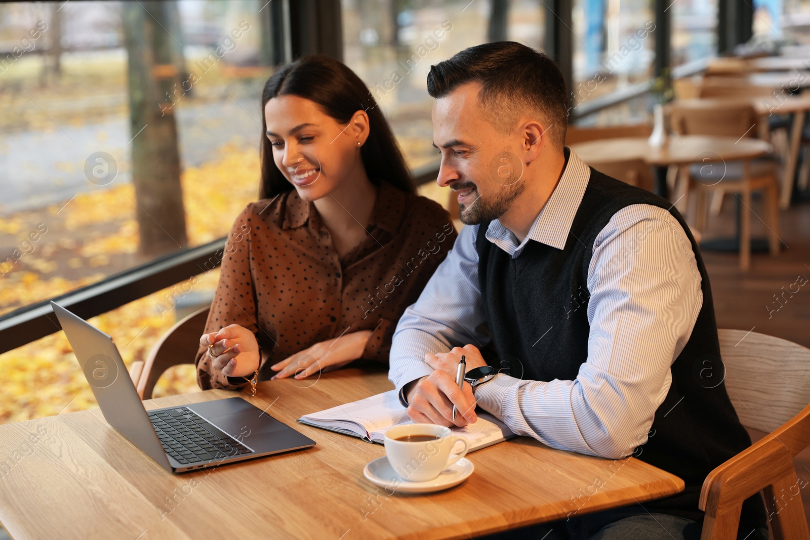 Photo of Colleagues with laptop working together in cafe