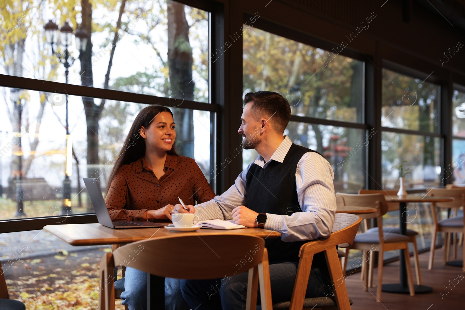 Photo of Colleagues with laptop working together in cafe