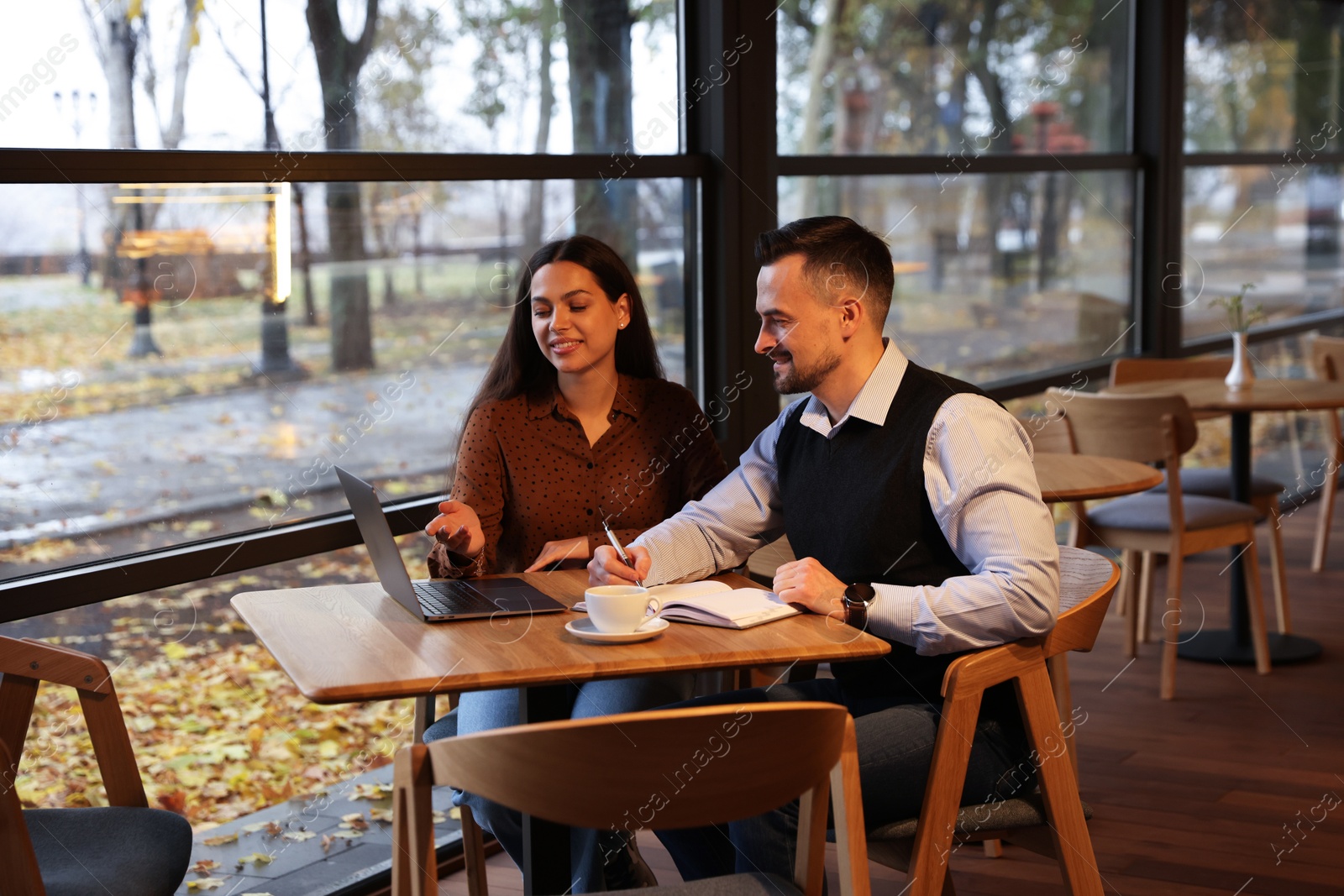 Photo of Colleagues with laptop working together in cafe