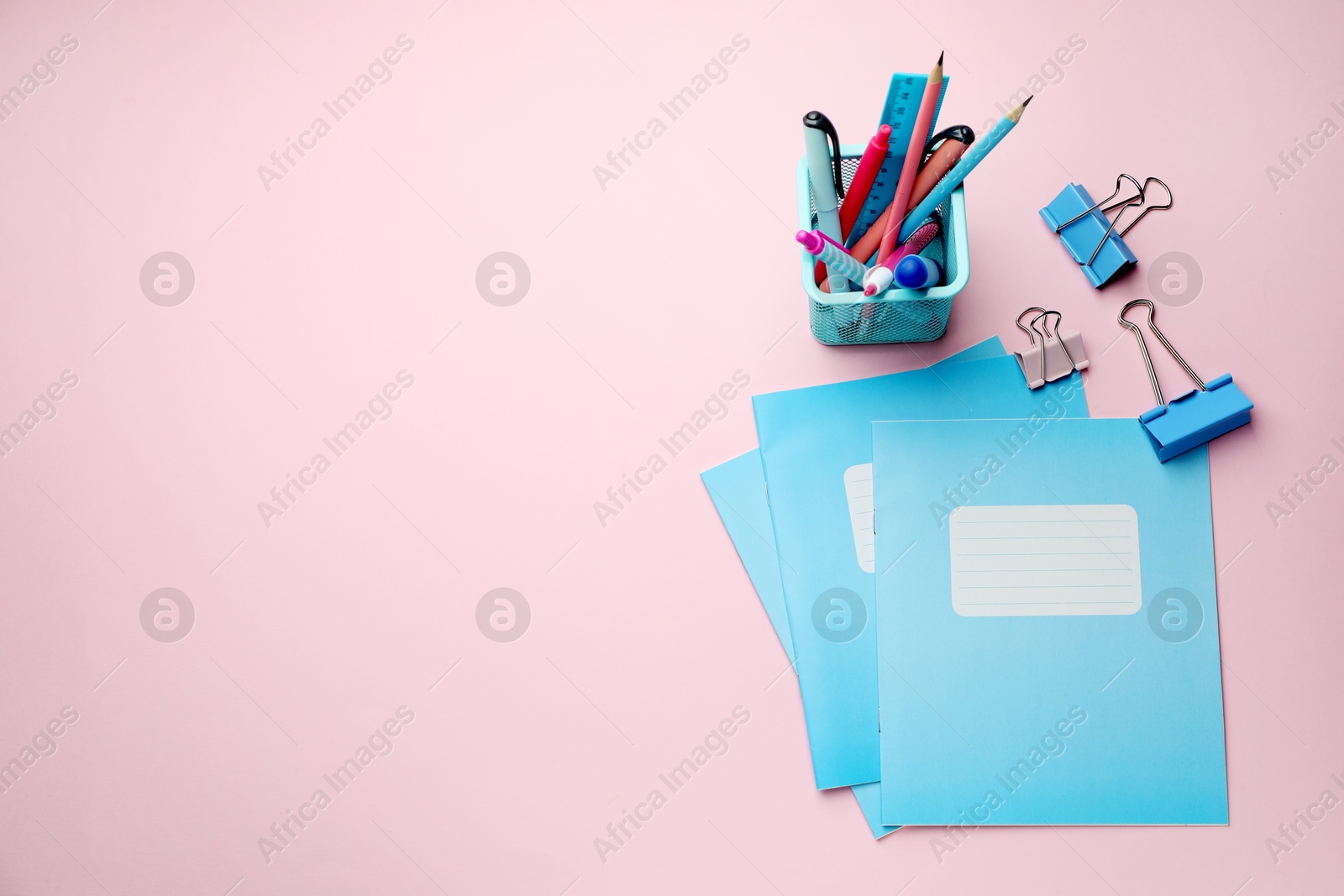 Photo of Copybooks and other school stationery on pink background, flat lay. Space for text