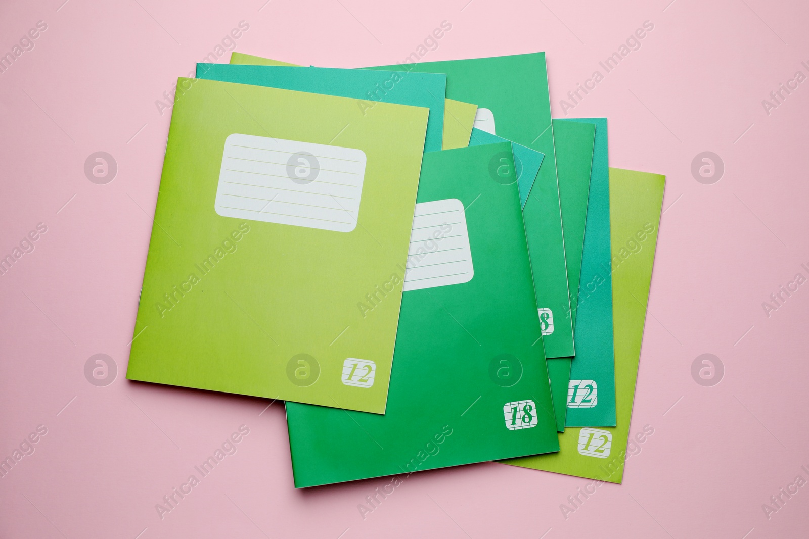 Photo of Colorful copybooks on pink background, flat lay. School stationery