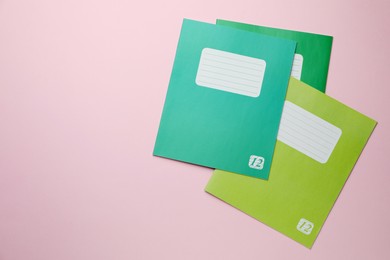 Photo of Colorful copybooks on pink background, flat lay. School stationery