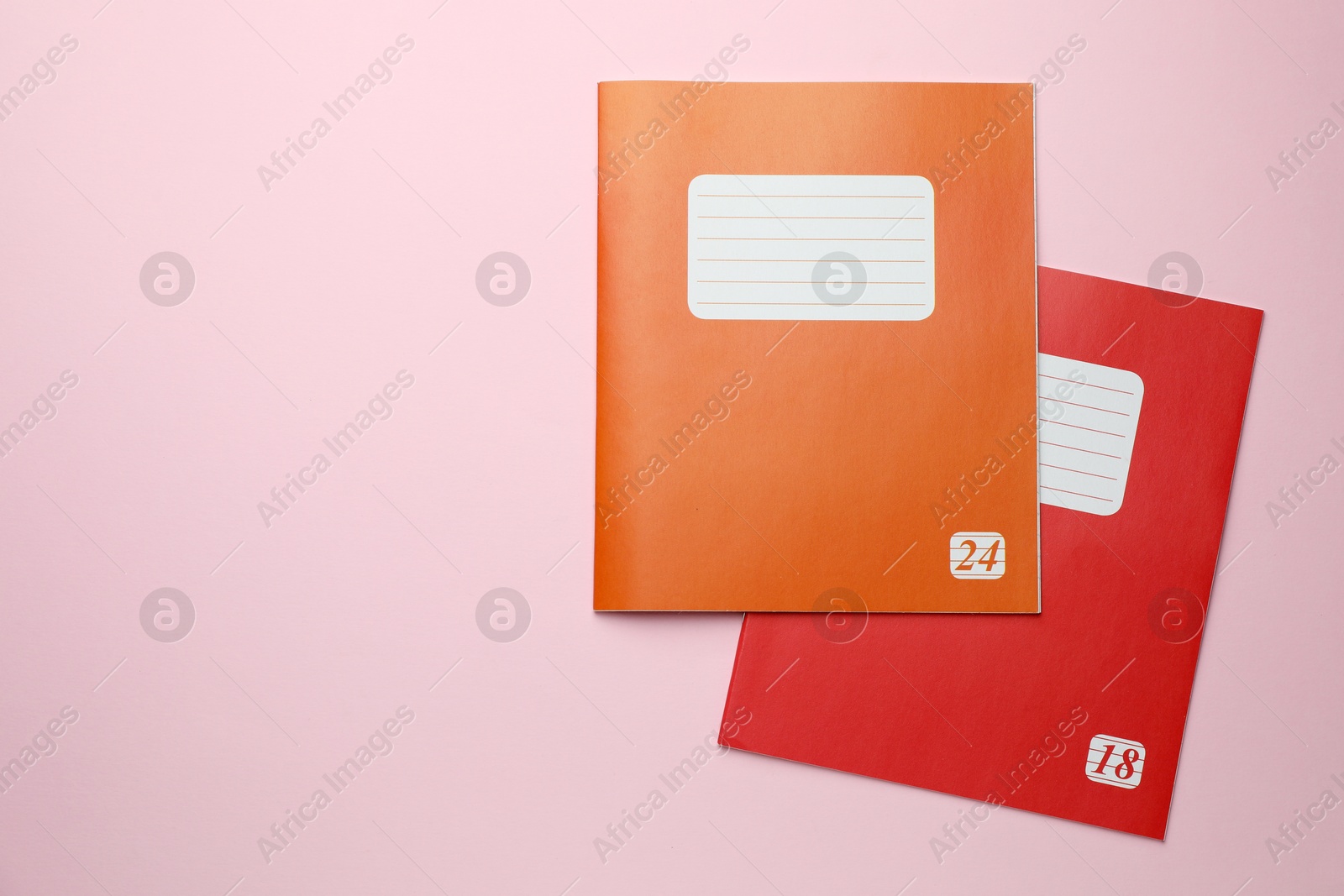 Photo of Colorful copybooks on pink background, top view. School stationery