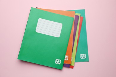 Photo of Colorful copybooks on pink background, flat lay. School stationery