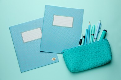 Photo of Copybooks and other school stationery on light blue background, flat lay