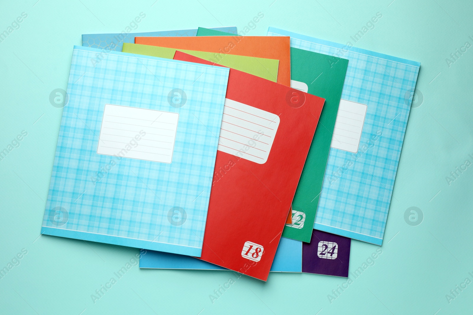 Photo of Colorful copybooks on light blue background, flat lay. School stationery