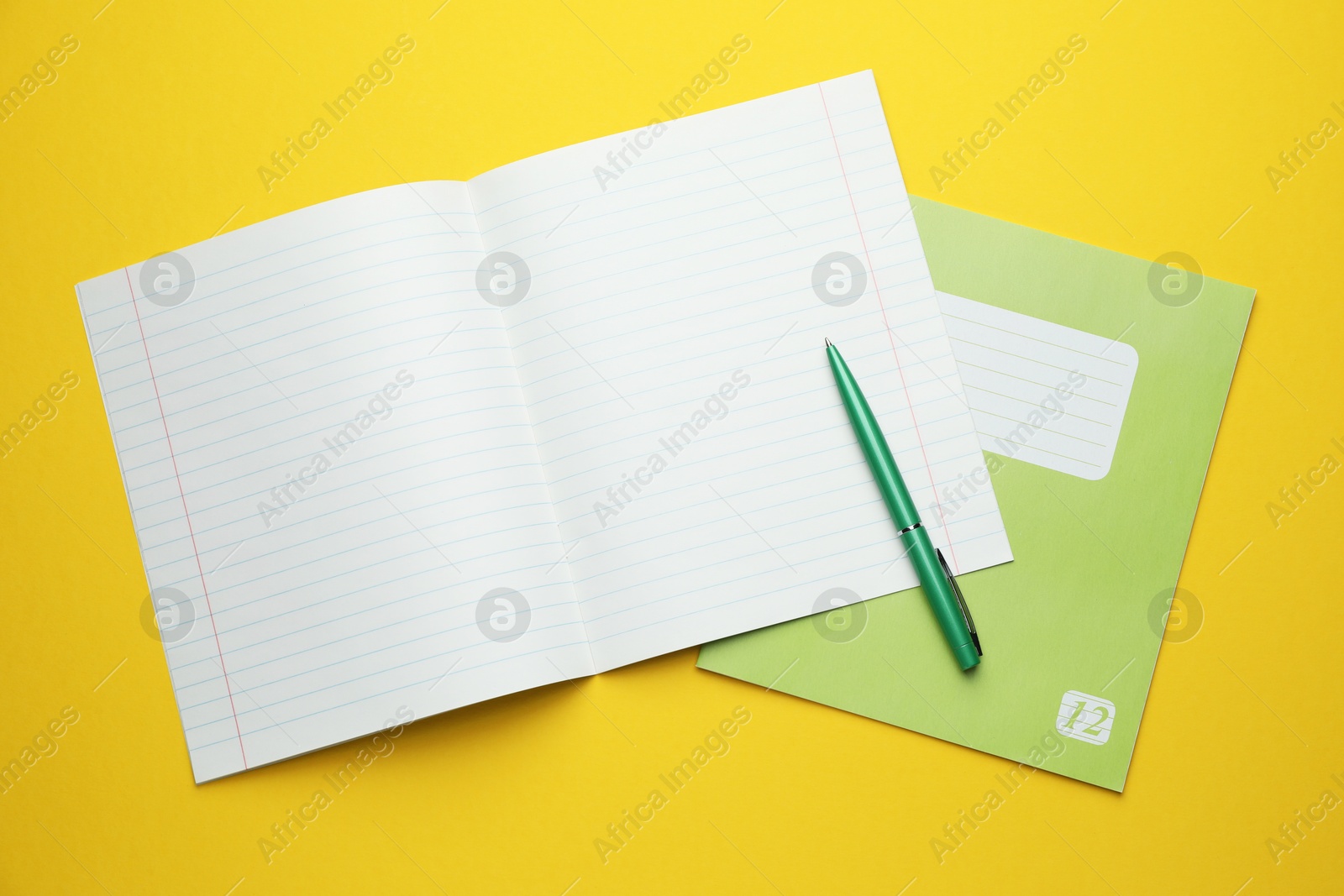 Photo of Copybooks and pen on yellow background, top view