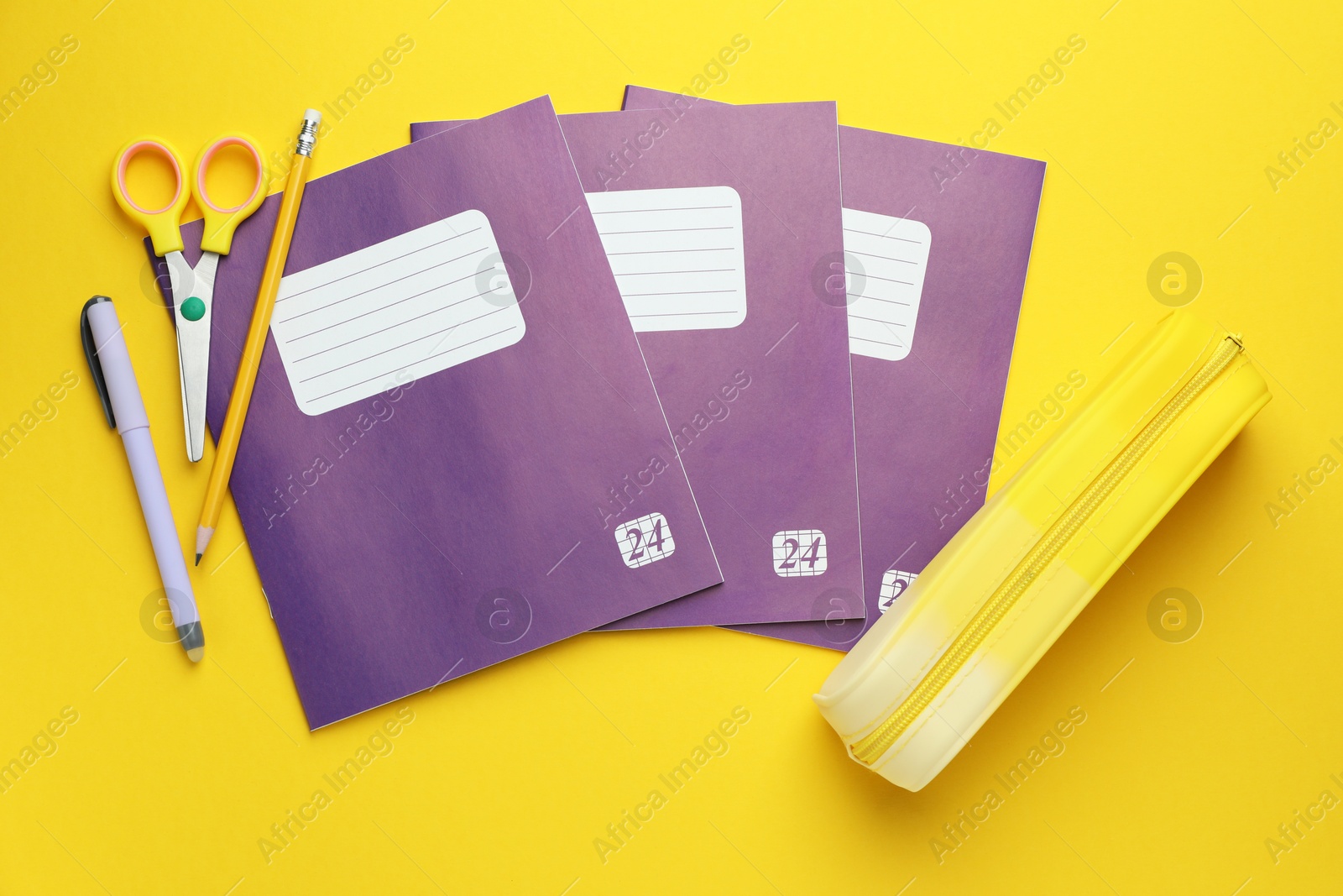 Photo of Copybooks and other school stationery on yellow background, flat lay