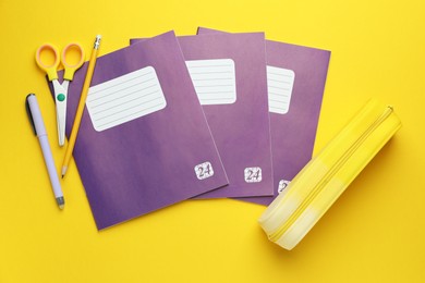 Photo of Copybooks and other school stationery on yellow background, flat lay