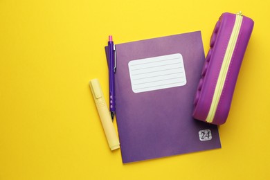 Photo of Copybook and other school stationery on yellow background, flat lay. Space for text