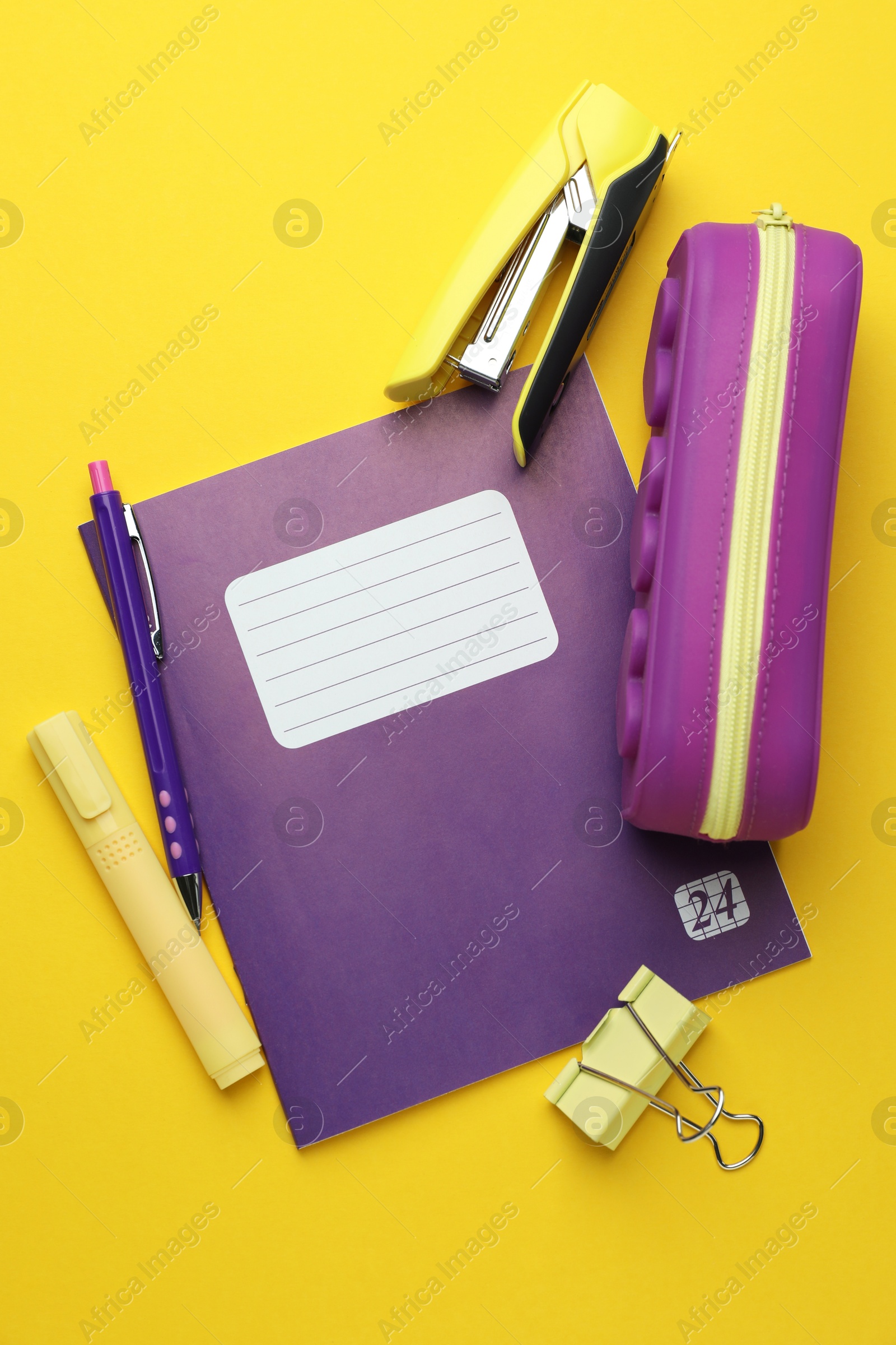 Photo of Copybook and other school stationery on yellow background, flat lay