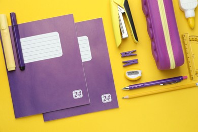 Photo of Copybooks and other school stationery on yellow background, flat lay