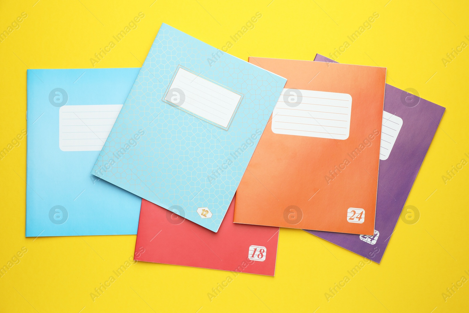 Photo of Colorful copybooks on yellow background, flat lay