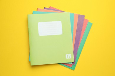 Photo of Colorful copybooks on yellow background, top view