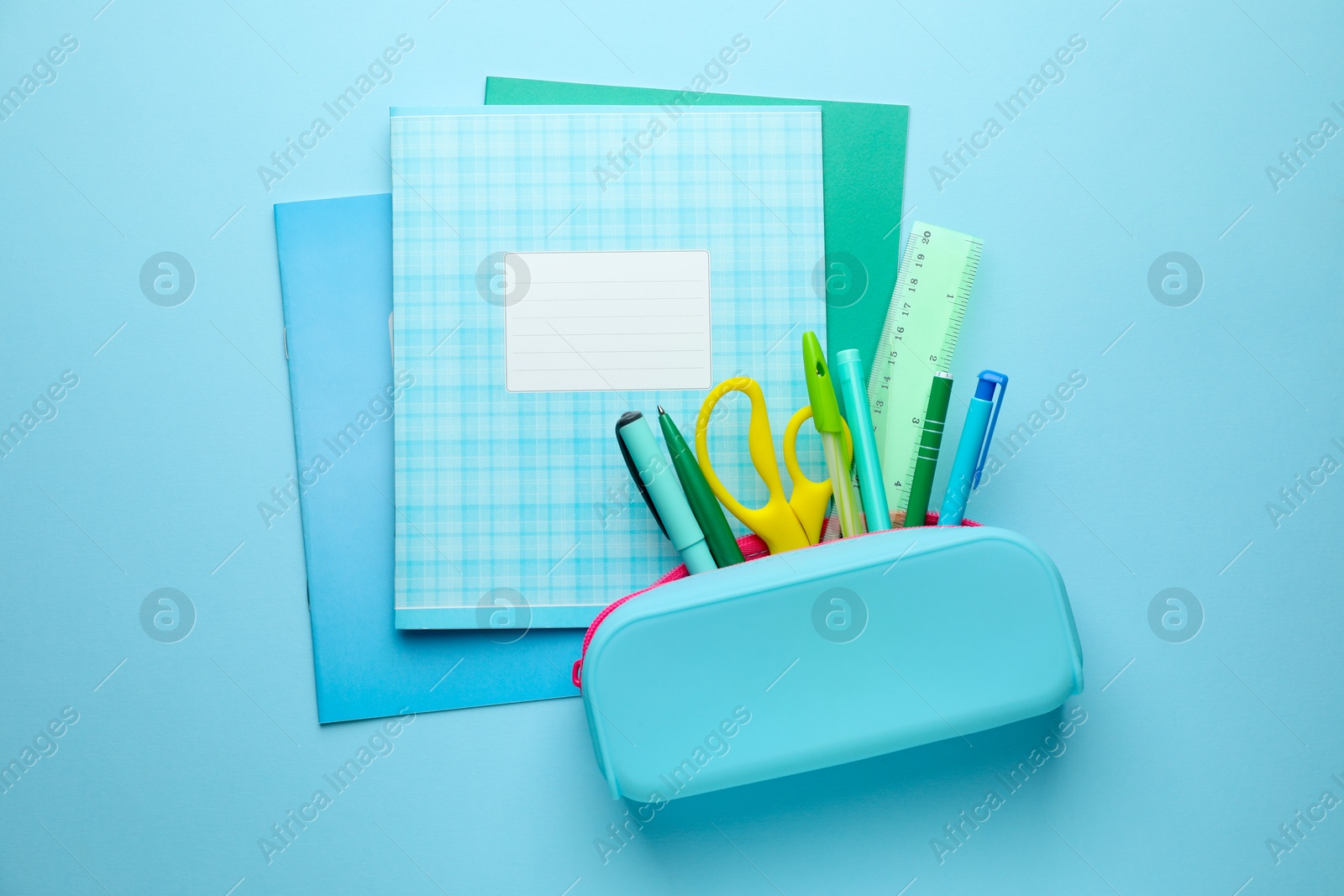 Photo of Copybooks and other school stationery on light blue background, flat lay