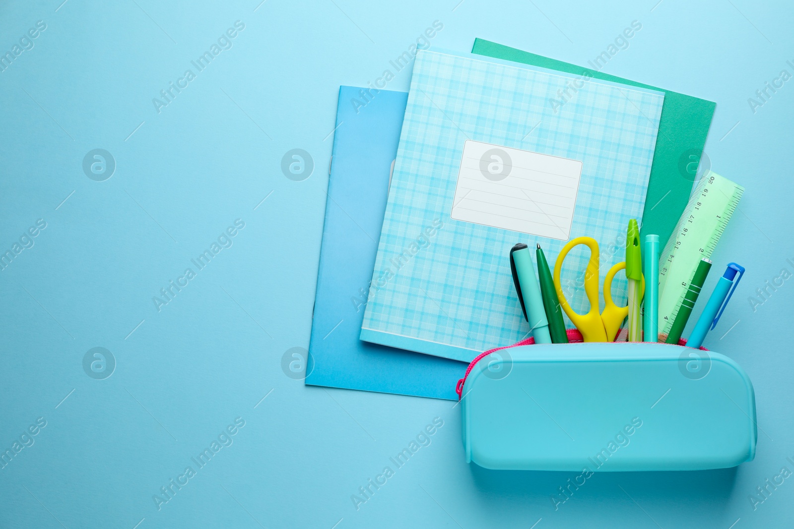 Photo of Copybooks and other school stationery on light blue background, flat lay. Space for text