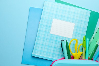 Photo of Copybooks and other school stationery on light blue background, flat lay